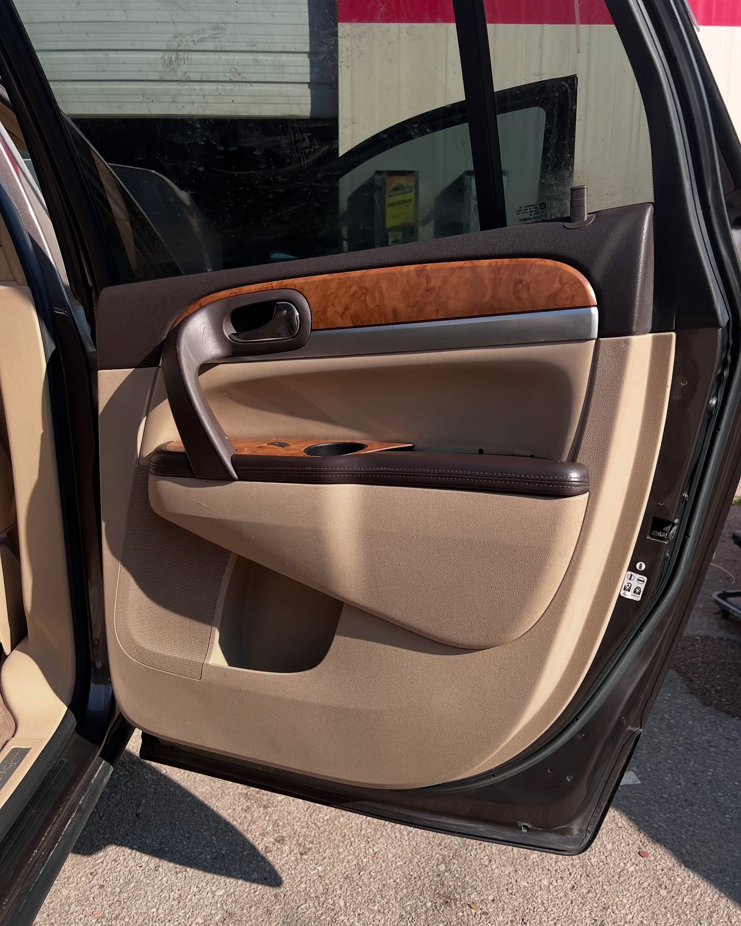 Clean tan and wood-trim rear driver door panel after ShineTime detailing